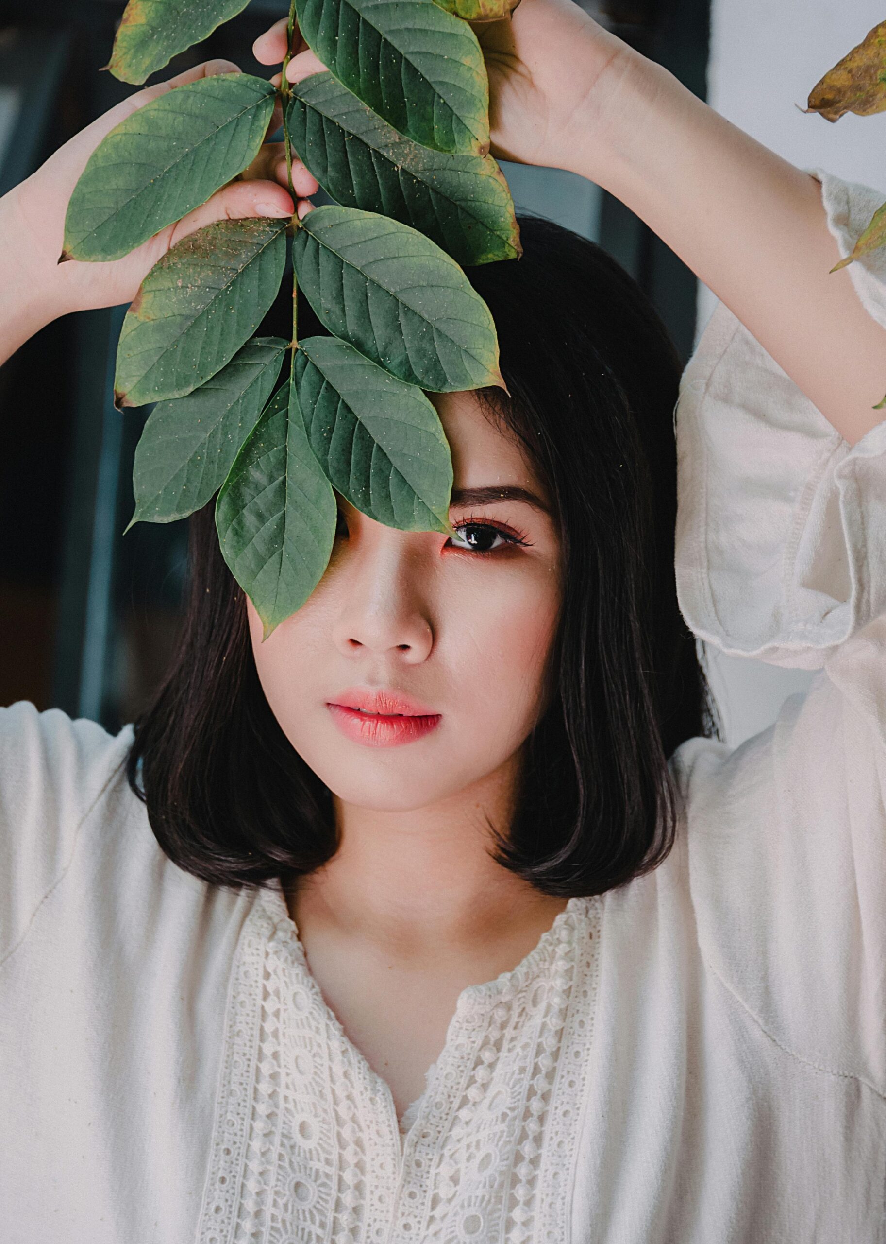 A stylish portrait of a young woman with green leaves, exuding natural beauty and elegance.